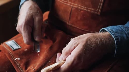 Man Carving Wooden Spoon With Knife in Workshop