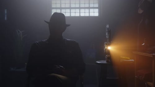 Silhouetted Figure Watching Vintage Film Projector in Dark Room