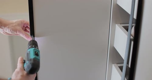 Using Screwdriver to Assemble Modern Wardrobe in Bright Home