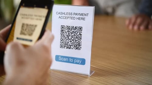Close Up Hands Of Woman Making A Quick And Easy Contactless Payment With Her Smartphone In A Cafe...