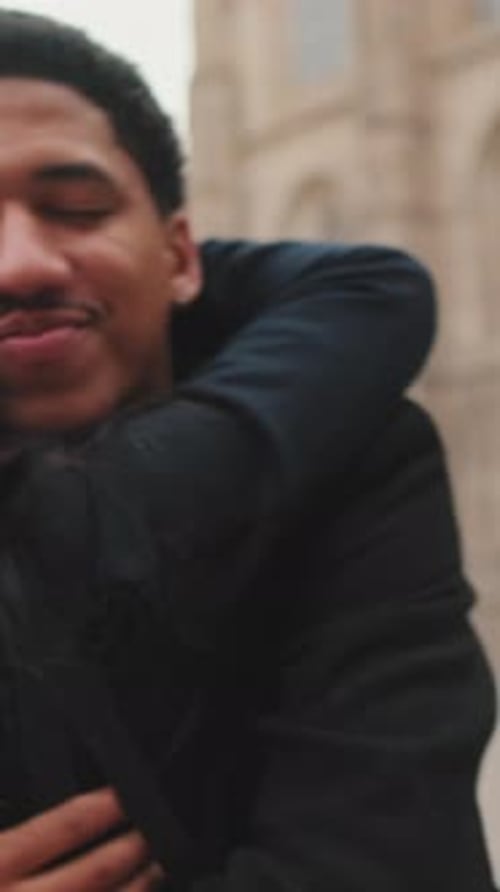 Young couple embracing in front of cathedral on cloudy day.