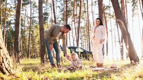 Family of father, mother and little son is outdoors in the forest at summertime
