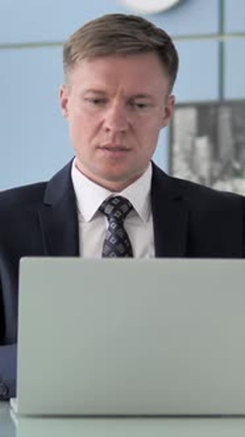 Pensive Businessman Works at Computer in Office
