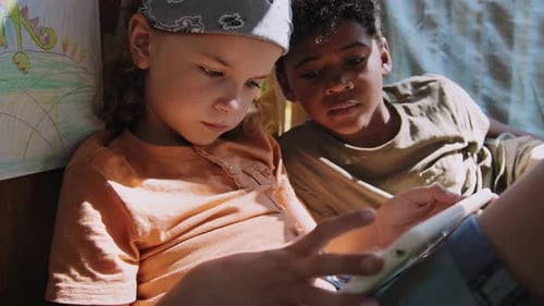 Two Children Play Tablet Together in Fort