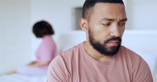 Worried Man in Bedroom with Woman in Background