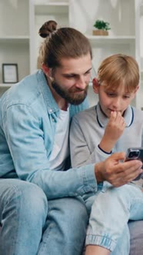 Dad and Son Watch Smartphone Together at Home