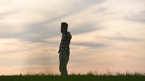 Enjoying freedom, hands to the sides. Handsome young man is on agricultural field. Beautiful sunligh