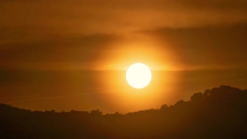 Timelapse of dramatic sunset with orange sky in a sunny day.