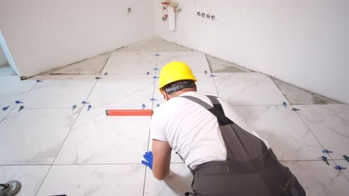 Construction Worker Laying Large Marble Floor Tiles