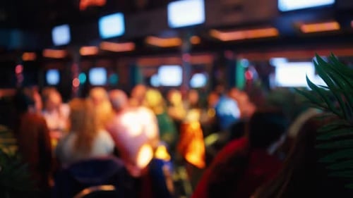 A Defocused Crowd Present in a Lively Social Venue Filled with Screens and Dynamic Activities