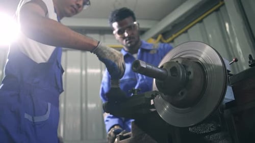 Diversity mechanic worker using metal lathe machine at the factory