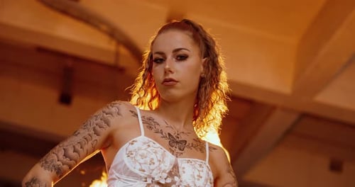 Tattooed woman with fire explosion behind – powerful cinematic, close-up, FPV gimbal movement