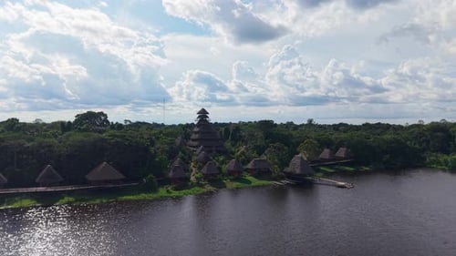 Aerial View of Wooden Thatched Bungalows Blending with Verdant Jungle Alongside Winding Amazon River