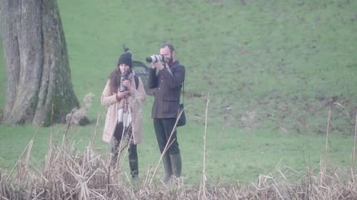 Photographer and Woman Photographing in Green Field