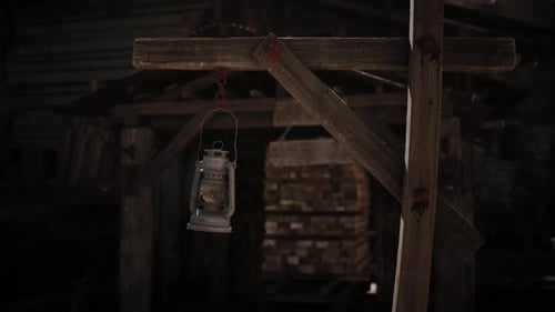 Old Lantern Swinging in Dark Rustic Wooden Barn