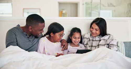 Family Relaxing in Bed with Tablet