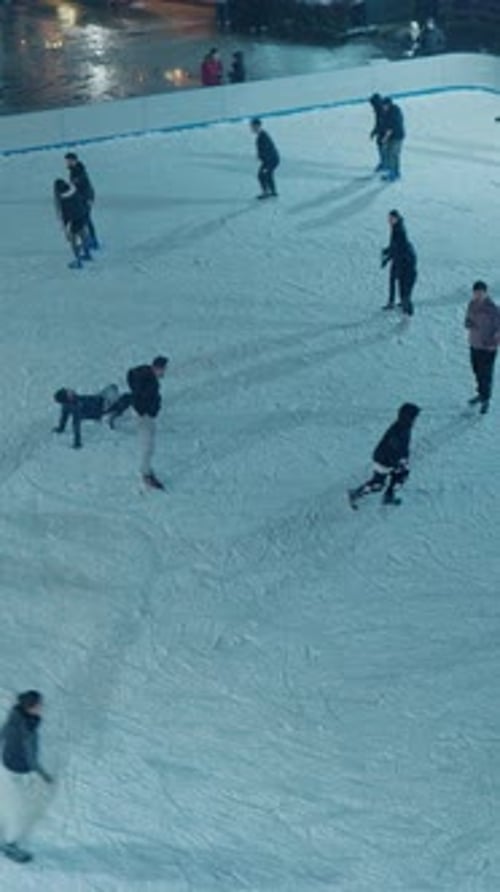 People skating on ice skating rink in park.