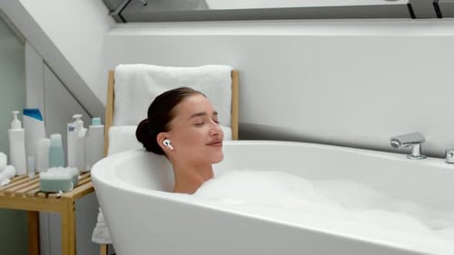 Woman Relaxes in a Bubble Bath with Headphones
