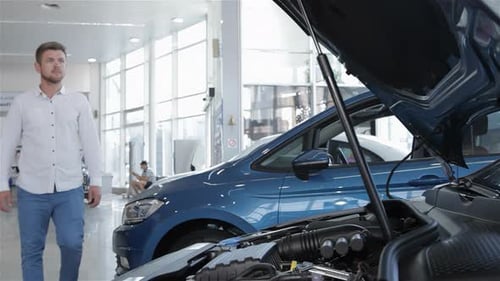 Un homme inspecte le compartiment moteur d'une voiture élégante chez le concessionnaire
