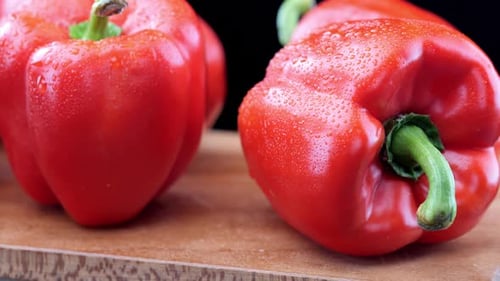 Fresh red peppers on wooden chopping board, close-up pan