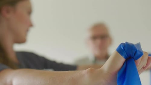 Senior Man Exercising with Caregiver Using Resistance Band