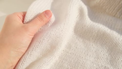 Handstreicheln in Nahaufnahme über die Oberfläche, gestricktes weiches Wolltuch oder warmer, flauschiger Pullover, handgefertigt