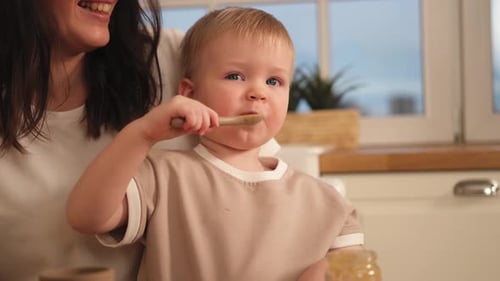 Mother Feeding Baby Tasty Food in Kitchen