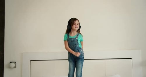 Energetic Girl Dances with Headphones on Bed
