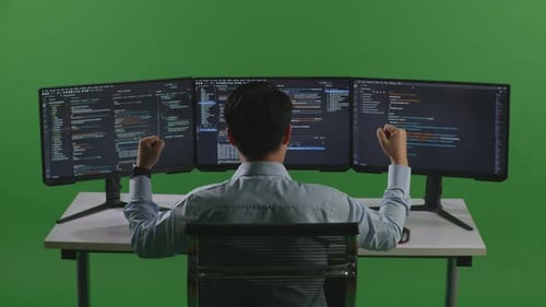 Happy Asian Man Celebrating While Write Code With Multiple Computer Screens In Green Screen