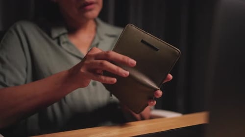 Woman takes money out of wallet and counts money while working at computer on table during economic