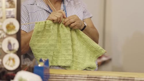 Hands Knitting a Light Green Textile Project