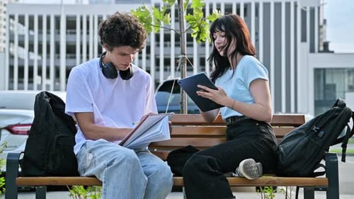 Two Young Adults Studying on a Park Bench