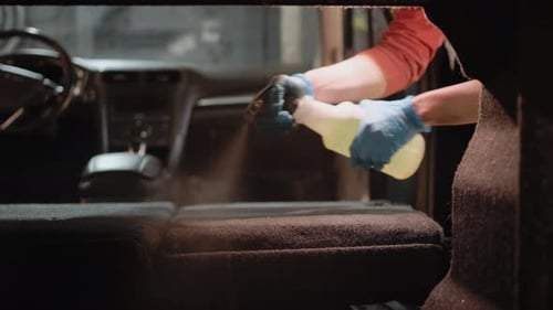 Worker sprays cleaning solution on car upholstery