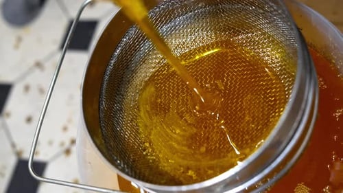 Golden Liquid Poured Through a Metal Strainer