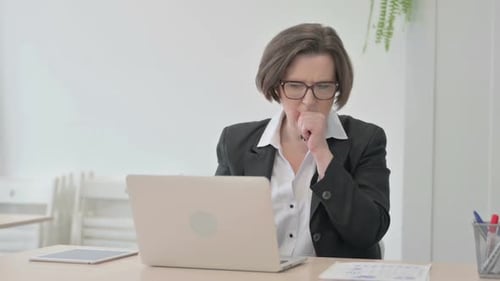 Woman Coughs at Desk Working on Laptop