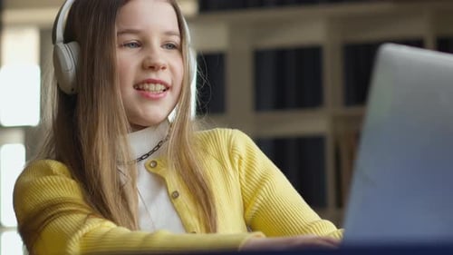 Girl Studies Using Laptop With Headphones at Home