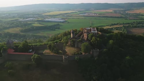 Aerial view of a historic Helfstyn castle with surrounding walls amidst a vast landscape