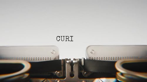 Old mechanical typewriter typing Curiosity in a close-up view.