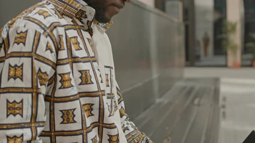 Afroamerikanischer freiberuflicher Mann, der im Freien am Laptop arbeitet