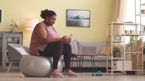 Woman Sits on Exercise Ball and Uses Cellphone