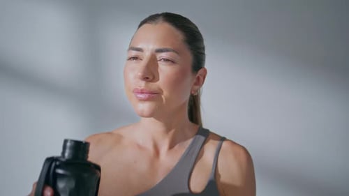 Exhausted Lady Drinking Water From Bottle After Fitness Training in Gym Closeup