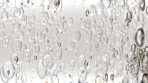 Gel fluide cosmétique transparent avec bulles de molécules et huile circulant dans un tube en verre avec liquide transparent