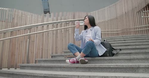 Woman Drinks Water on Urban Steps