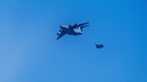 Large Military Transport Aircraft Flying Together with Fighter Jet Behind USA
