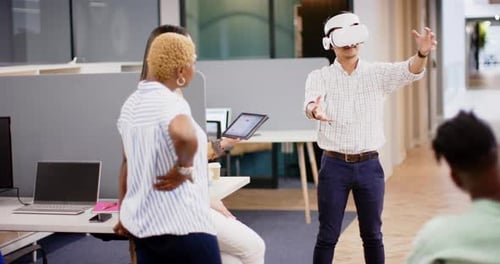 Using VR headset, man demonstrating virtual reality to colleagues in office