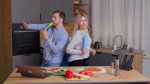 Cheerful Couple Dancing While Making Pizza Together
