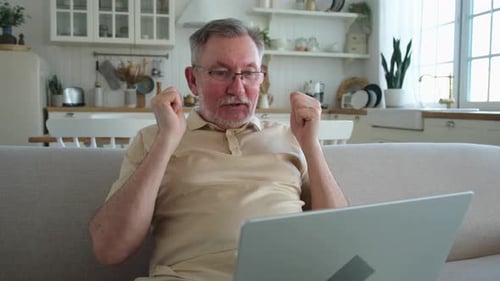 Senior Man Video Chatting on Laptop at Home