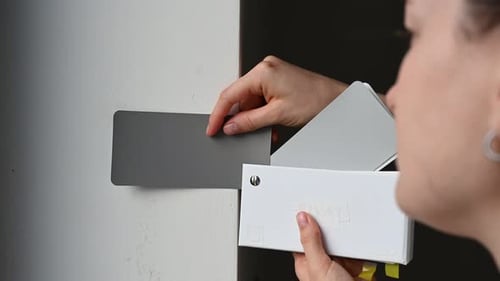 Woman Comparing Paint Swatches to Wall Colors