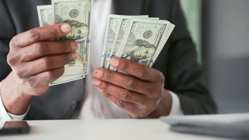 Close up Male hands count one hundred dollar US bills. African american businessman in formal suit
