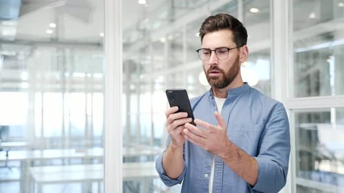 Surprised Man Reacts to Phone News in Office